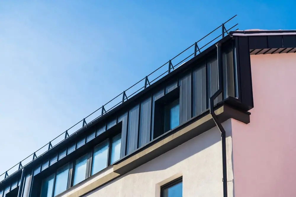 Close-up of a commercial building showing installed metal gutters and downspout along the roof edge for proper water drainage