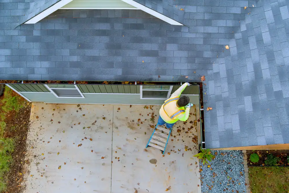 Technician performing commercial gutter cleaning, debris removal, and condition assessment from an overhead view