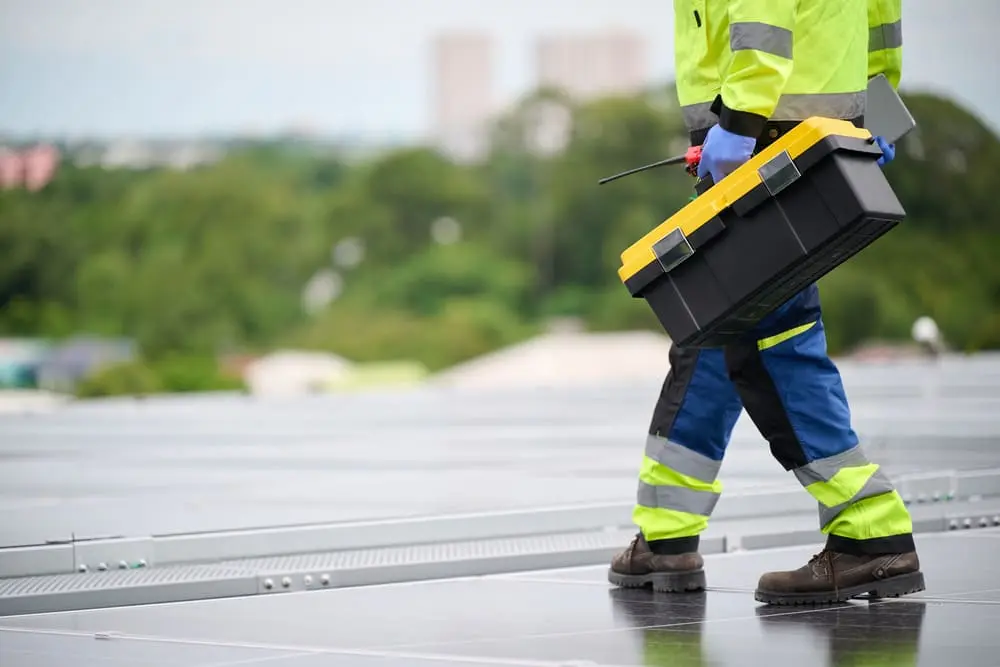 Commercial roofing technician performing routine maintenance on a flat roof to identify issues early and prevent costly repairs.