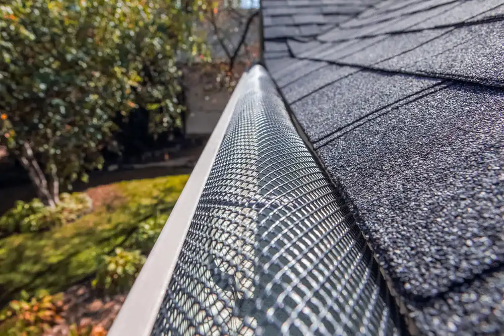 metal mesh gutter guards installed along a roof edge to prevent clogs, reduce maintenance, and protect the home from water damage