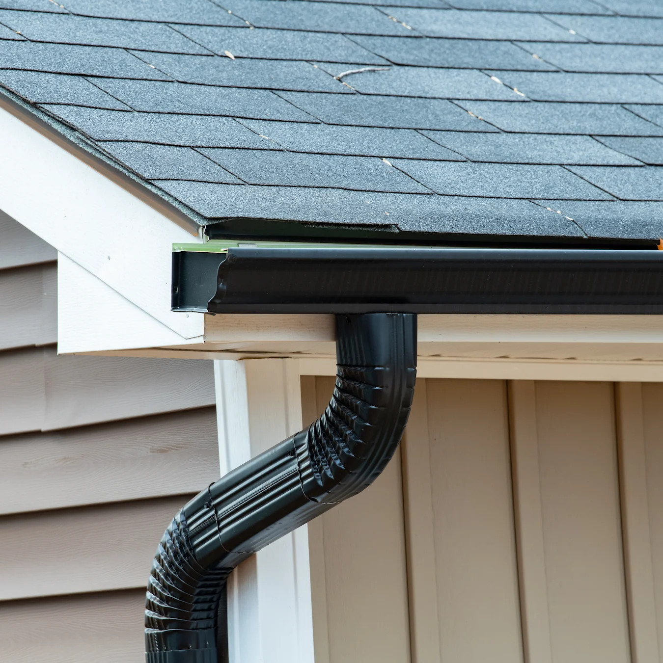 New black gutters installed along a residential roof edge
