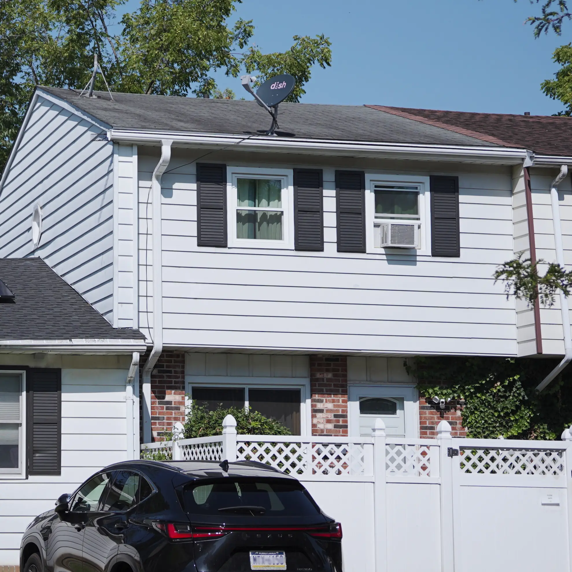 Two-story home with white siding, black shutters, and brick facade
